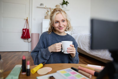 Portrait of young woman using mobile phone while sitting at home