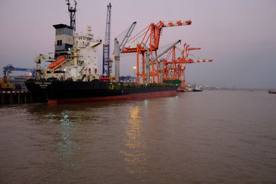 Cranes at harbor against sky