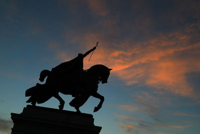 Low angle view of angel statue against sky during sunset