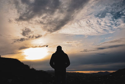 Rear view of silhouette man standing against sky during sunset