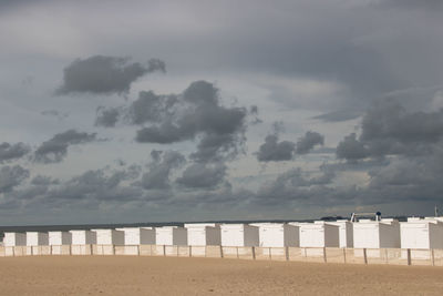 Hooded chairs on beach against sky