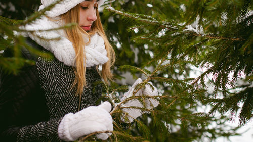 Young woman wearing warm clothing while standing by trees during winter
