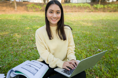 Portrait of a smiling young woman sitting on field