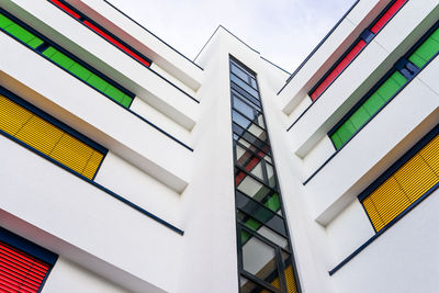 Elevation of a modern office building with different colors of blinds on each floor.