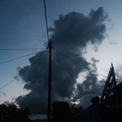 Low angle view of power lines against cloudy sky