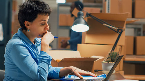 Side view of young woman using laptop at table