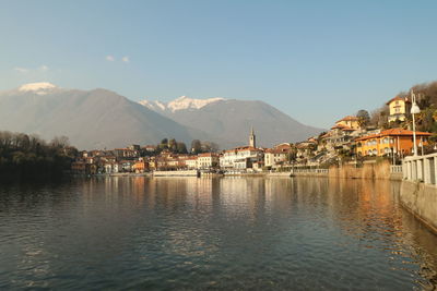 Buildings by river against sky