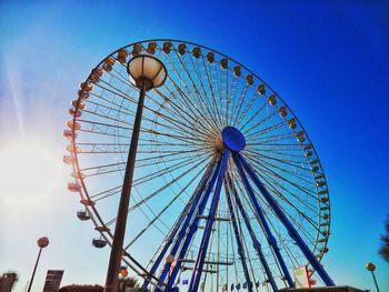 Low angle view of ferris wheel against clear blue sky
