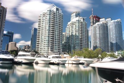 Boats moored in river by city against sky