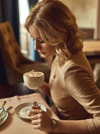 Side view of woman sitting with coffee cup at cafe