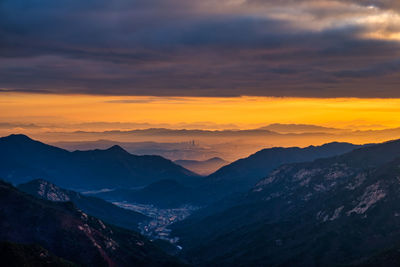 Scenic view of mountains against dramatic sky during sunset