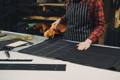 Seamstress at work. dressmaker cutting fabric. woman standing at table with cut textile and working