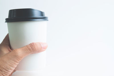 Close-up of hand holding bottle against white background