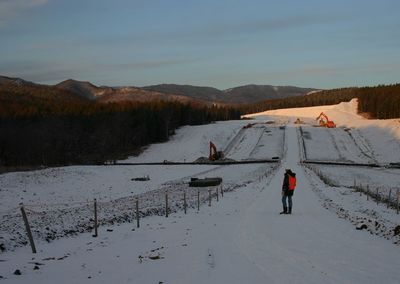 Person on snow covered field against sky