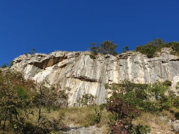 Low angle view of rock formation against clear blue sky