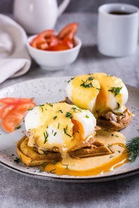 Eggs benedict and bacon on a crispy waffle on a plate for homemade breakfast. vertical view