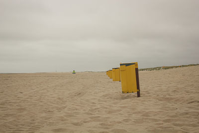 Hooded beach chair on shore against sky