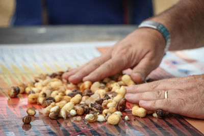 Cropped image of hand touching peanuts on table