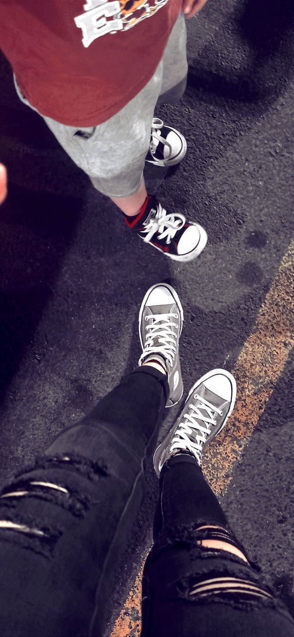 low section, black, shoe, human leg, sneakers, red, one person, blue, footwear, white, limb, standing, human limb, lifestyles, clothing, high angle view, men, walking shoe, spring, casual clothing, leisure activity, personal perspective, canvas shoe, day, adult, sports, jeans, city, outdoors