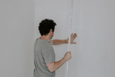 Caucasian plasterer man checks the evenness of the walls after puttying.