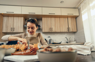 Craftsmanship, woman in sunlit kitchen, attentively, pastry creation, baking tools, ingredients 