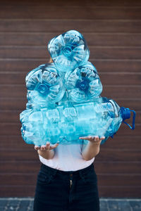 Young woman throwing out empty used plastic water bottles into trash bin. collecting plastic waste