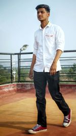 Young man walking on building terrace against sky