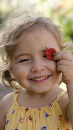 Close-up portrait of smiling girl holding leaf