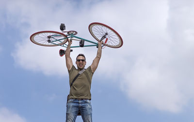 Low angle view of man with bicycle against sky