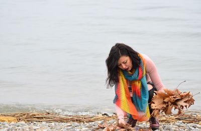 Beautiful woman collecting dry leaves at beach