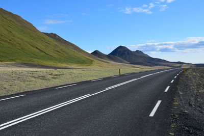 Scenic view of road by mountains against sky