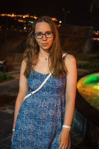 Portrait of young woman standing against blurred background