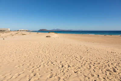 Scenic view of beach against clear blue sky