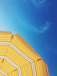 Low angle view of yellow umbrella against blue sky