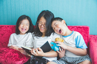 Happy friends looking away while standing on bed