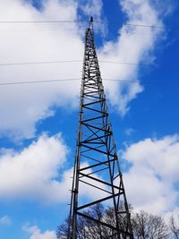 Low angle view of electricity pylon against blue sky