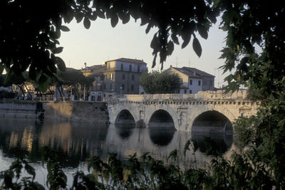 Arch bridge over river against buildings in city