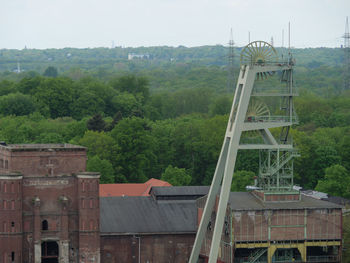 Built structure by trees and buildings against sky