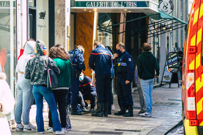 Rear view of people walking on footpath in city