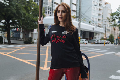 Portrait of young woman standing on road in city