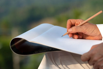 Midsection of person with book and pencil