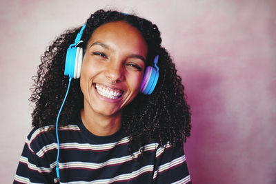 Portrait of smiling young woman against wall