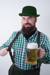 Portrait of hipster with beer glass standing against gray background