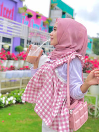 Midsection of woman holding pink while standing outdoors