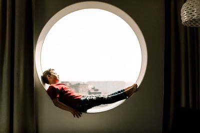 Full length of boy lying on circular window