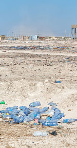 Garbage on sand at beach against clear blue sky