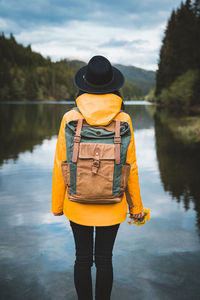 Rear view of man standing by lake against sky
