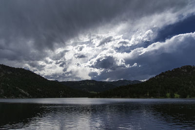 Scenic view of lake and mountains against cloudy sky