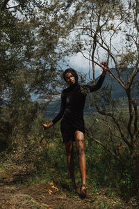 Full length portrait of young woman standing in forest