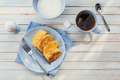 Breakfast with fried croutons, yogurt and black tea on light wooden background. summer country food